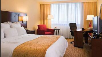 Une chambre d’hôtel avec un grand lit, un bureau équipé d’un ordinateur, une chaise et un téléviseur.