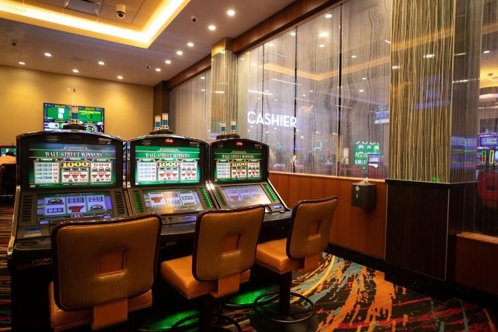 Un espace de jeux de casino comprenant plusieurs machines à sous, un guichet de caisse et donnant sur la salle de casino.