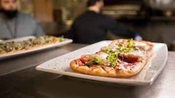 A pizza on a white plate with toppings, in a restaurant setting.