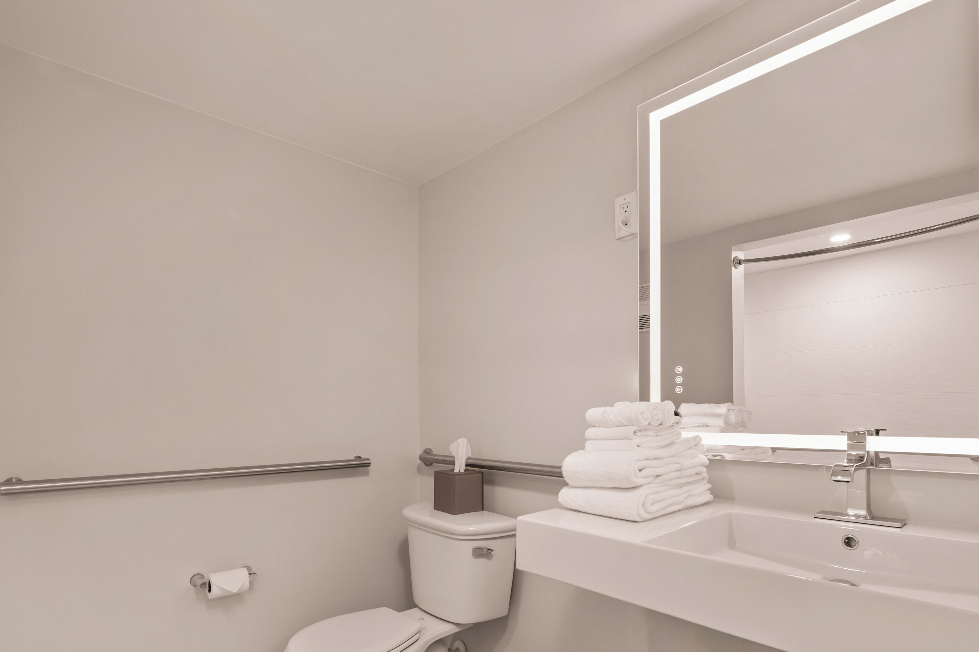 A modern bathroom with a toilet, sink, and mirror.