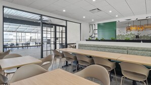 A modern office space with a long table and chairs, a green accent wall, and a view through large windows. - B&B Hotel Orlando International Drive Near Universal - Newly Renovated! (Orlando)
