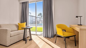 A modern living room with a sofa, a small round table, a yellow chair, and a desk with a lamp. - B&B Hotel Orlando International Drive Near Universal - Newly Renovated! (Orlando)