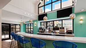 Un espace bar moderne avec des tabourets de bar bleus, un comptoir blanc et une cuisine en arrière-plan.