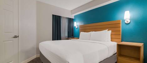 A hotel room with a large bed, wooden headboard, two bedside tables, and a nightstand.