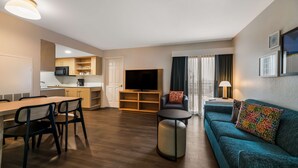 Un salon moderne avec un coin repas, un canapé, un téléviseur et une cuisine en arrière-plan.