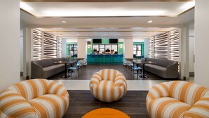 Un hall d’entrée spacieux avec un bar central, des espaces aménagés pour s’asseoir et un lustre moderne.