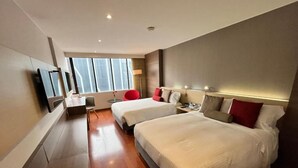 Een moderne hotelkamer met twee bedden, een televisie, een bureau en een rode stoel.
