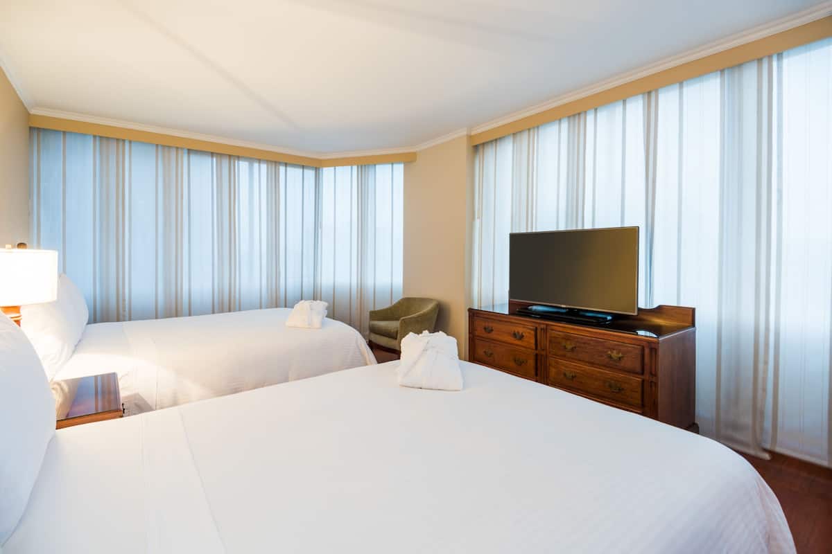 Een hotelkamer met twee bedden, een televisie, een houten dressoir en een stoel.