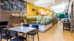 Een café met een prikbord, een glazen vitrine met gebak en een geruite vloer.
