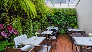 Een binnentuin met tafels en stoelen, omgeven door weelderig groen.
