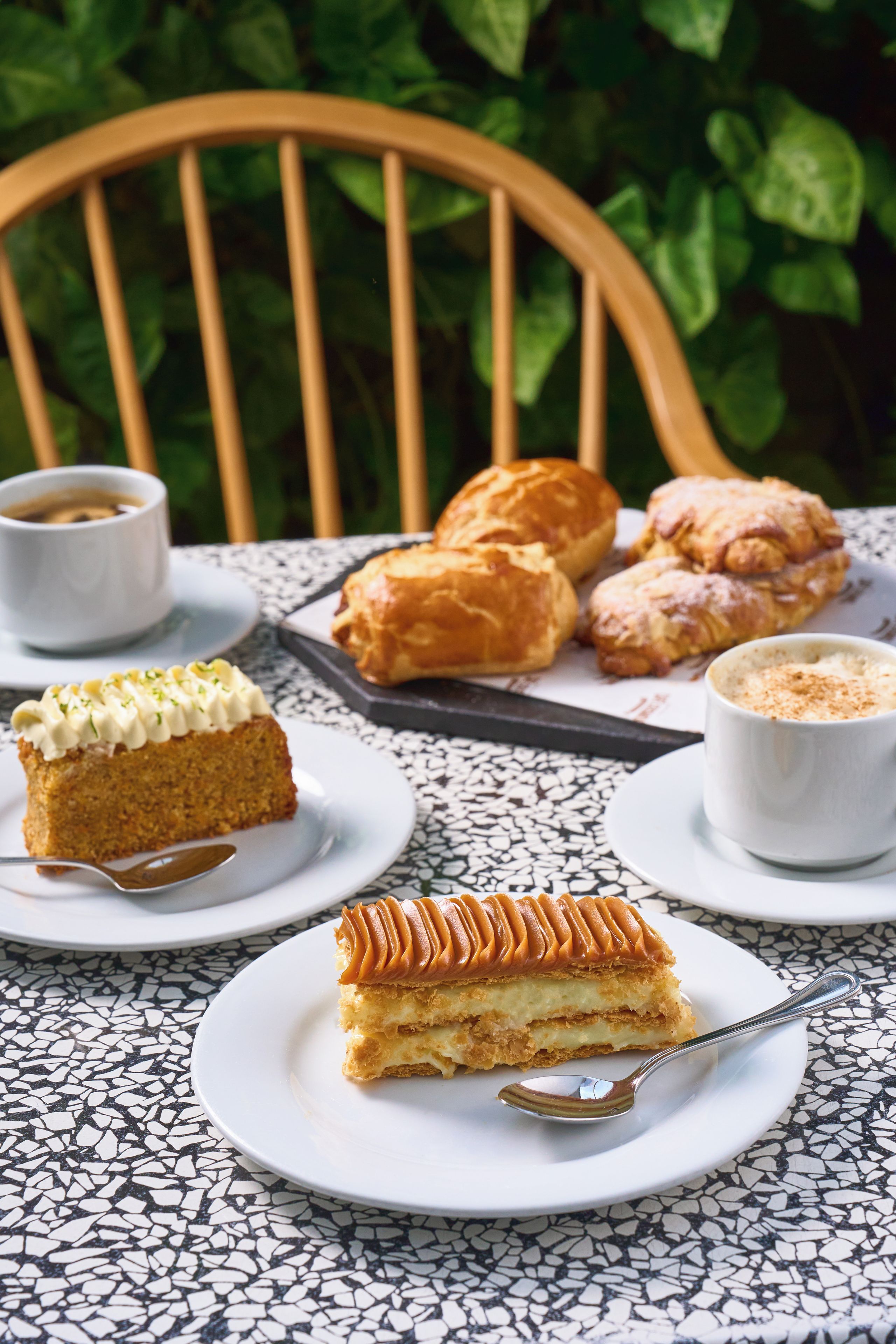 Une table avec des pâtisseries, une part de gâteau et deux tasses de café.