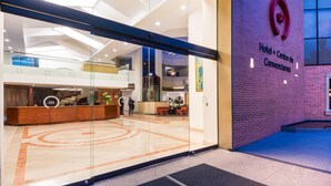 Un hall d’hôtel comprenant un comptoir d’accueil, une grande entrée vitrée et une enseigne indiquant le nom de l’hôtel.