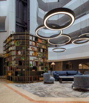 A modern interior with a multi-level bookshelf, circular pendant lights, and a blue sofa.