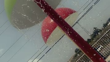 A view of a swimming pool area with a water slide, a red pole, and a green structure.