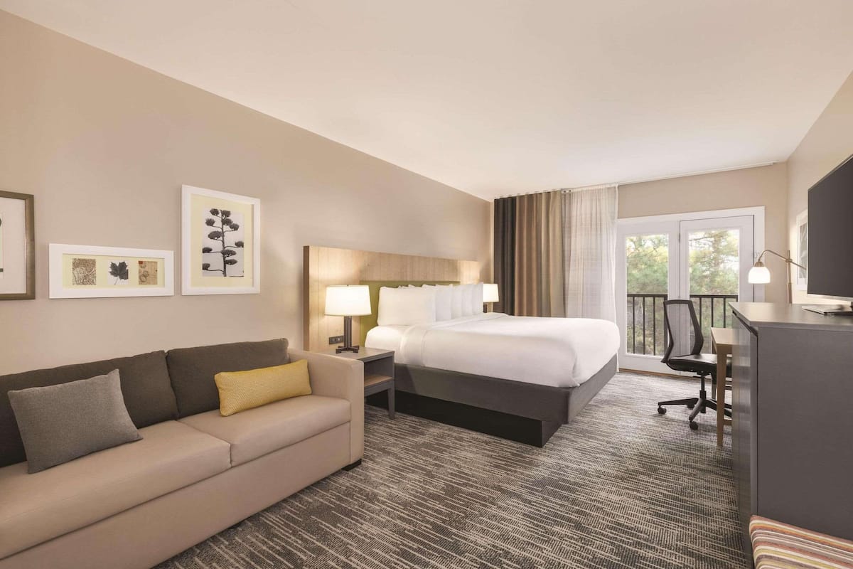 A hotel room with a bed, a sofa, a desk, and a TV.