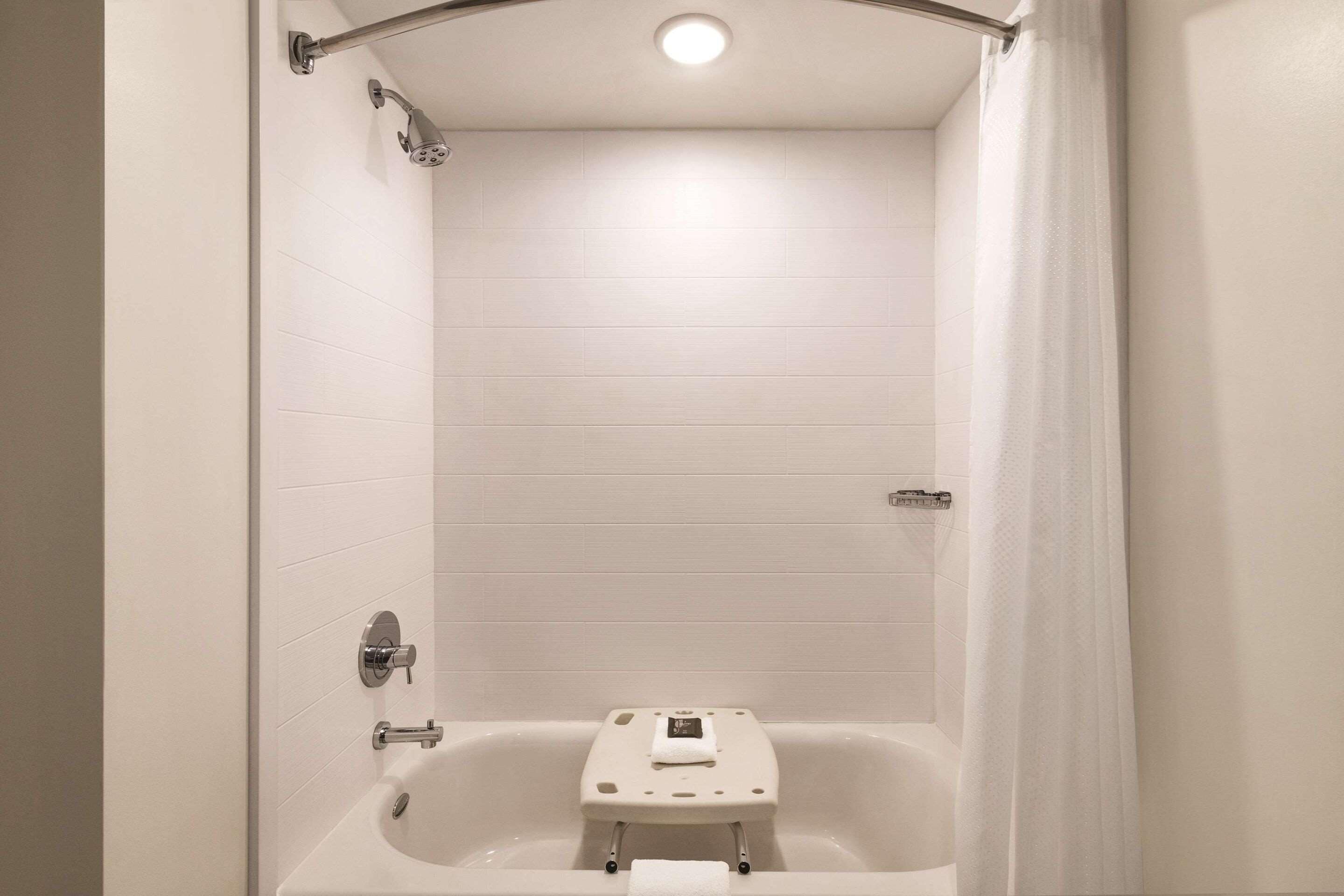 A modern bathroom with a bathtub, a handheld showerhead, and a towel rack.