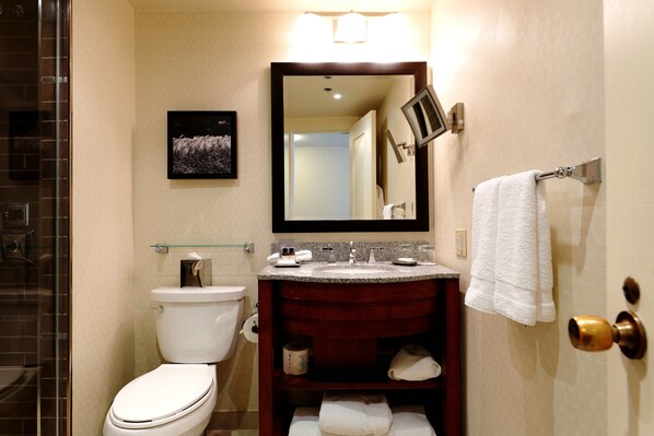 A bathroom with a toilet, sink, and mirror.
