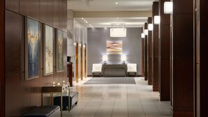 A modern hotel lobby with a long reception desk, seating area, and artwork on the walls.