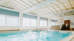 An indoor swimming pool with clear water, marked depth levels, and a tiled floor.