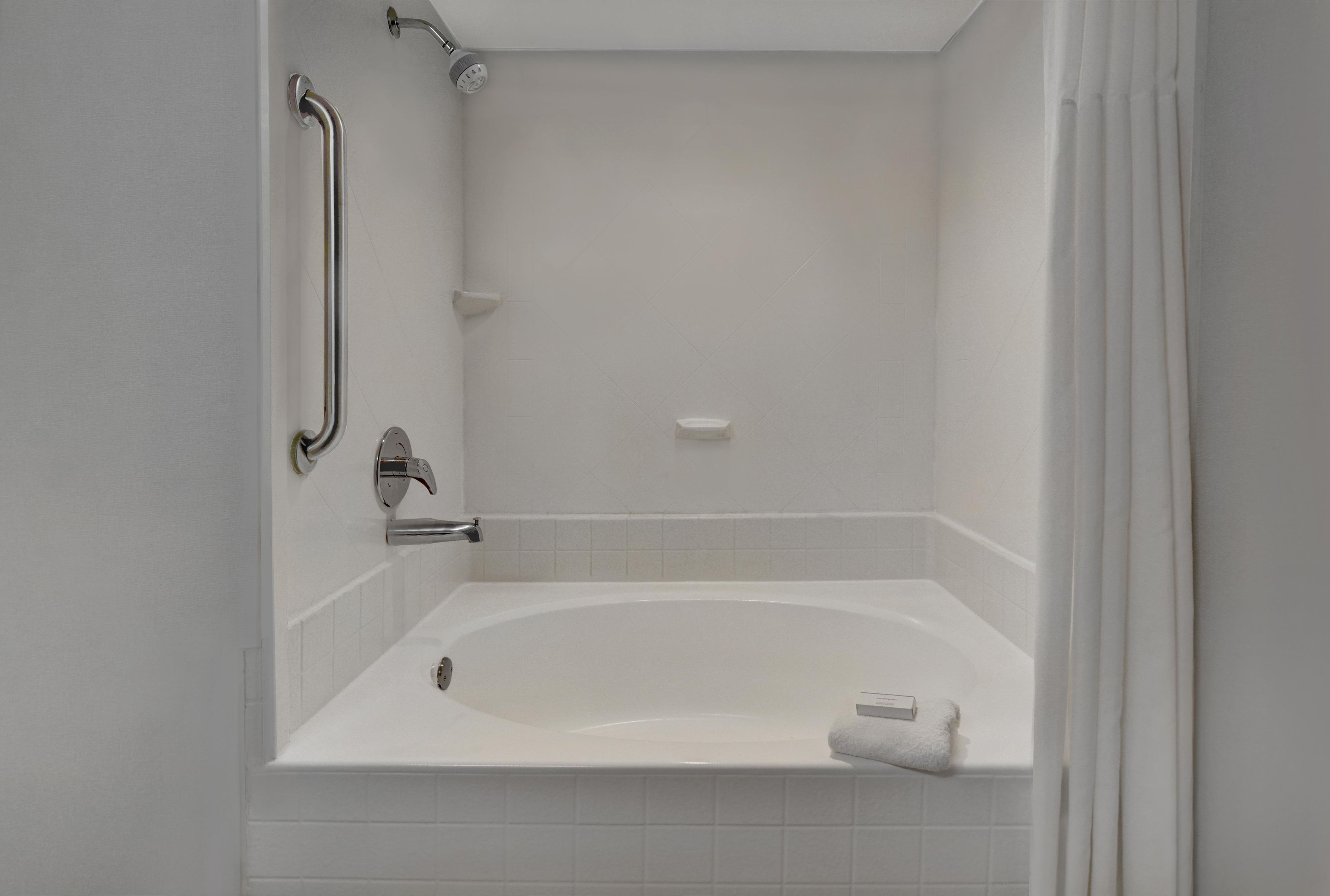 Eine weiße Badewanne mit einer Duschbrause und einem Handtuchhalter.