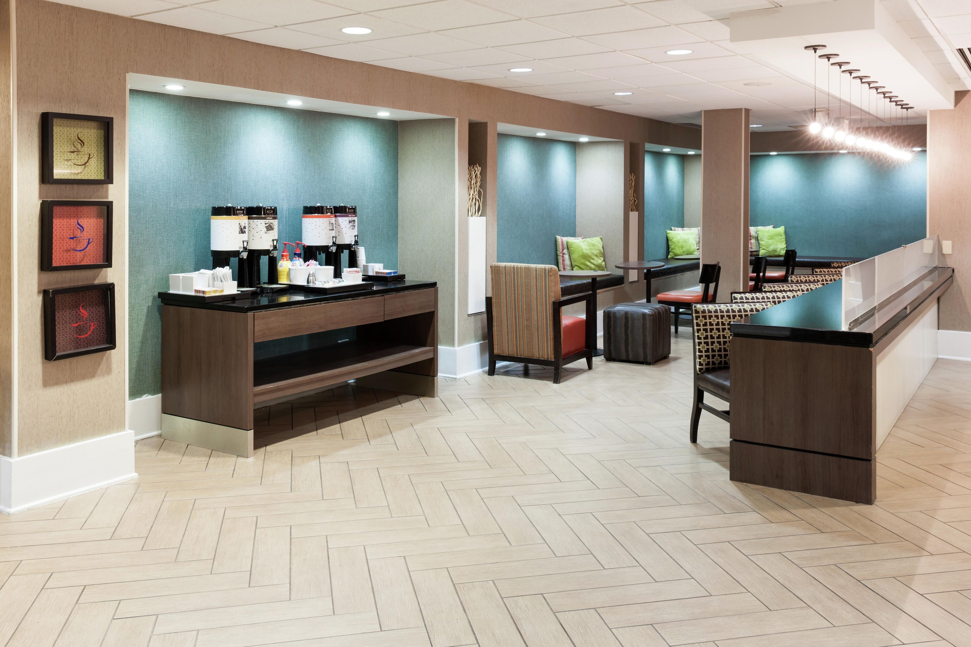 A hotel lobby with a reception desk, seating area, and a herringbone-patterned floor.