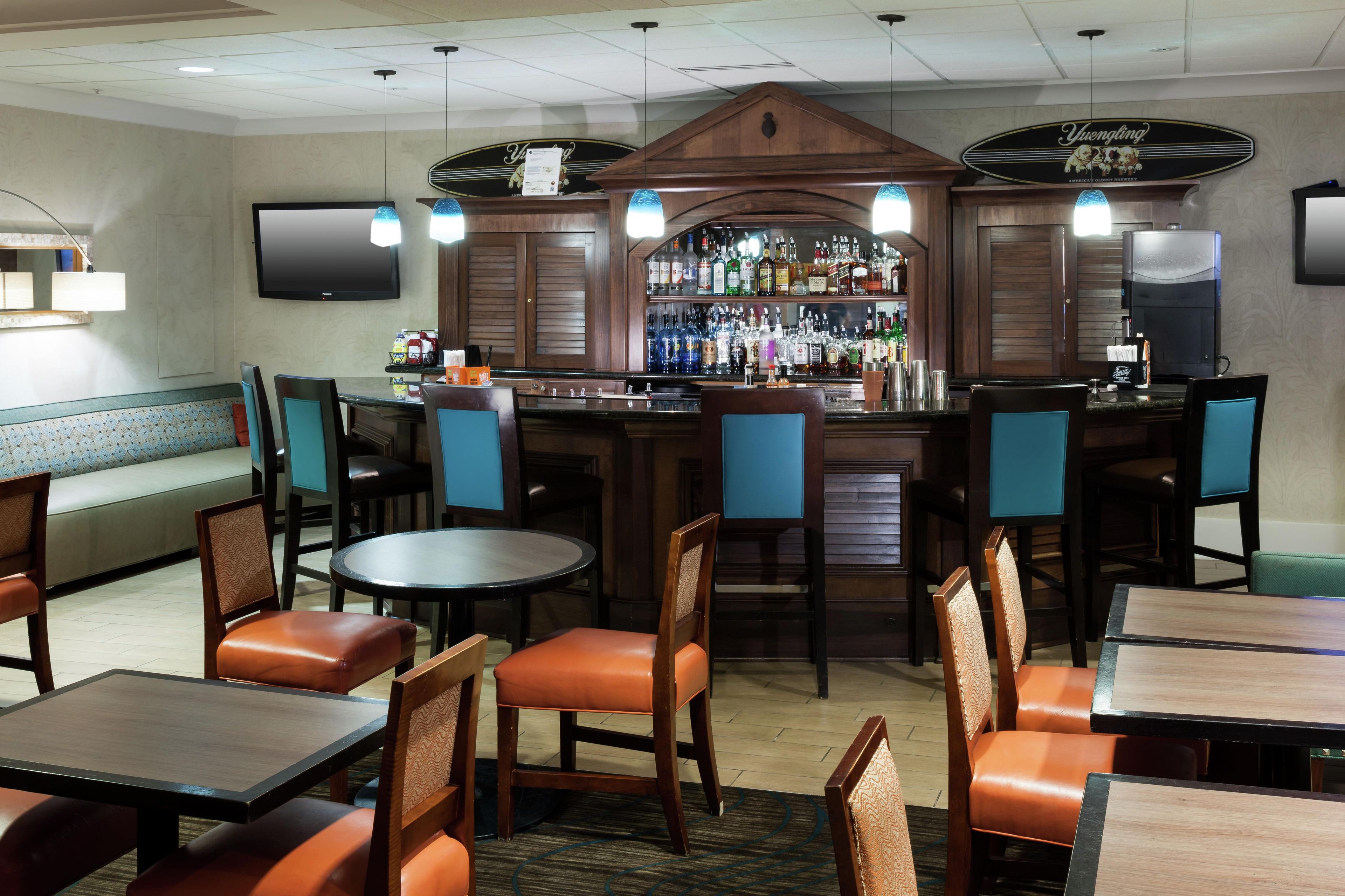 A bar area with multiple seating options, including booths and tables, and a bar counter with a variety of bottles.