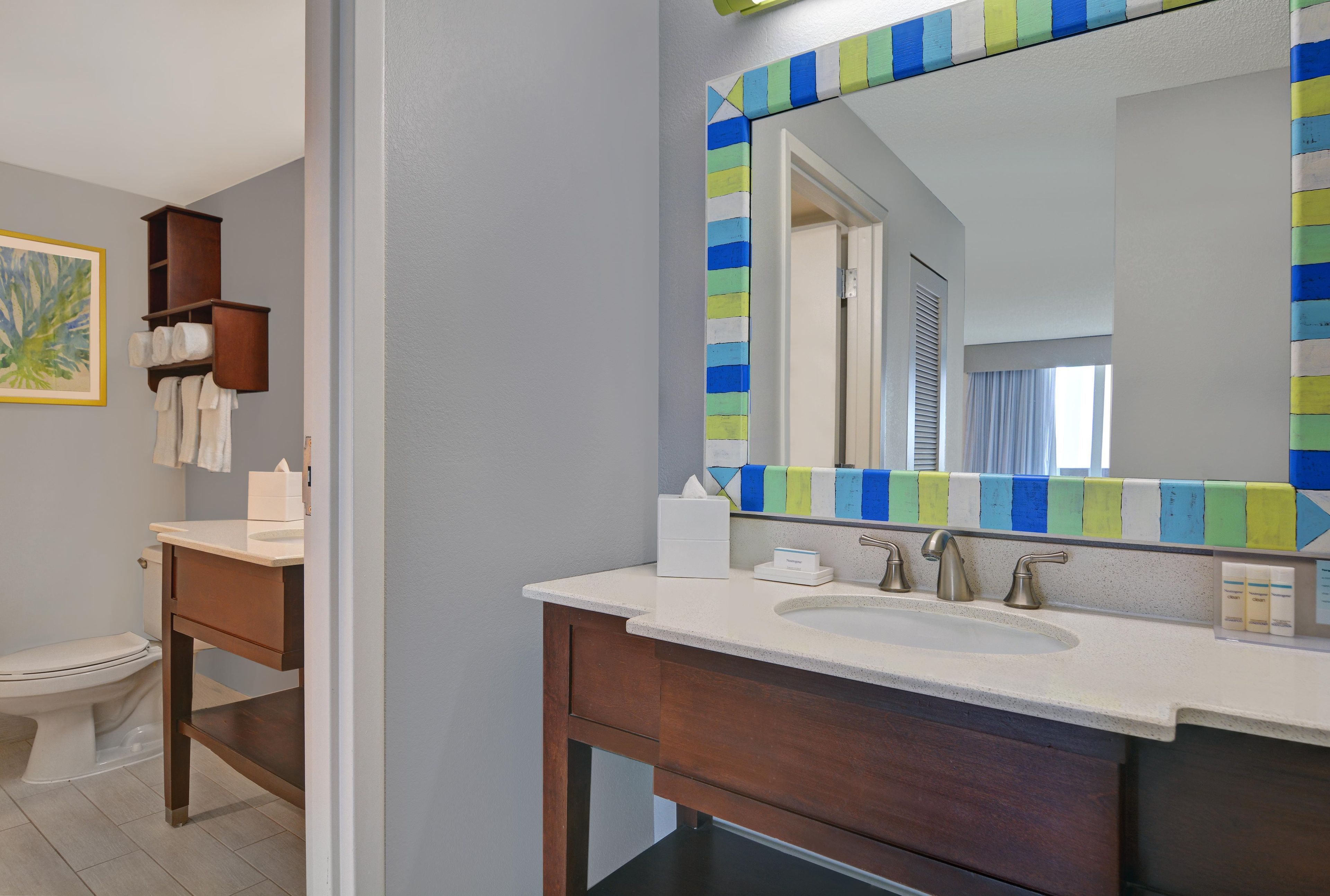 Un baño con tocador de madera, un espejo grande y un inodoro.