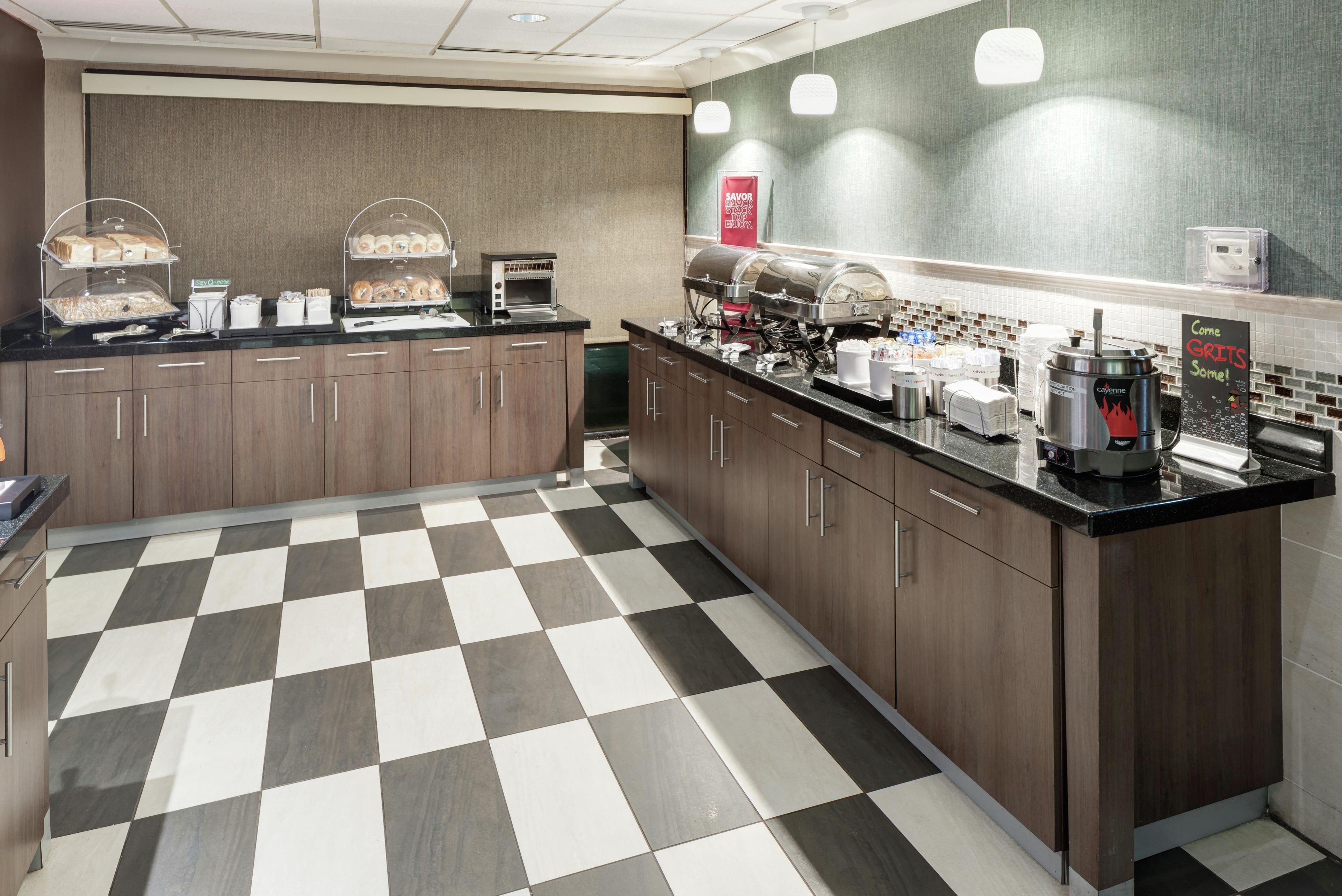 A hotel kitchen with checkered flooring, a coffee station, and a buffet area.