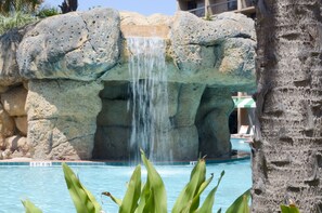 Una piscina con una cascada, rodeada de grandes formaciones rocosas.
