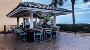 A bar with a tiled roof, outdoor seating, and a view of the ocean. - Hampton Inn Jacksonville Beach/Oceanfront (Jacksonville Beach)