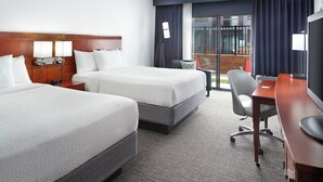 A hotel room with two beds, a desk, a chair, and a TV. - Courtyard by Marriott Raleigh Midtown (Raleigh)