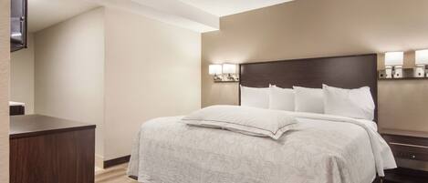 A hotel room with a bed, bedside tables, a desk, and a wall-mounted lamp.