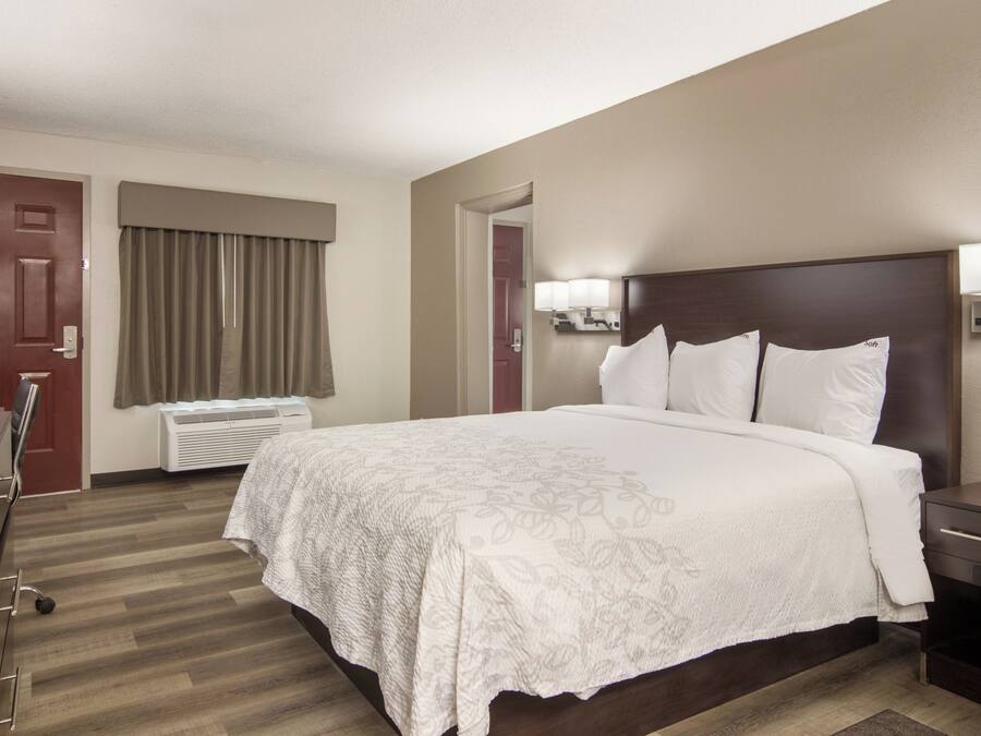 Una habitación de hotel con una cama grande, un escritorio, una silla, un armario y la puerta del baño.