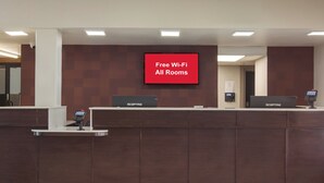 A reception desk with a digital screen displaying 'Free Wi-Fi All Rooms.' - Red Roof Inn PLUS+ & Suites Erie (Erie)