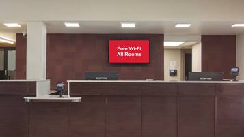 Un comptoir d’accueil doté d’un écran numérique affichant la mention : « Wi-Fi gratuit dans toutes les chambres ».