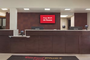 Una recepción con una pantalla digital que muestra 'Wi-Fi gratuito en todas las habitaciones'.