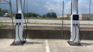 Two electric vehicle charging stations labeled 'AUTEL' at a parking lot with a chain-link fence, concrete barriers, and a clear sky. - Red Roof Inn PLUS+ & Suites Erie (Erie)
