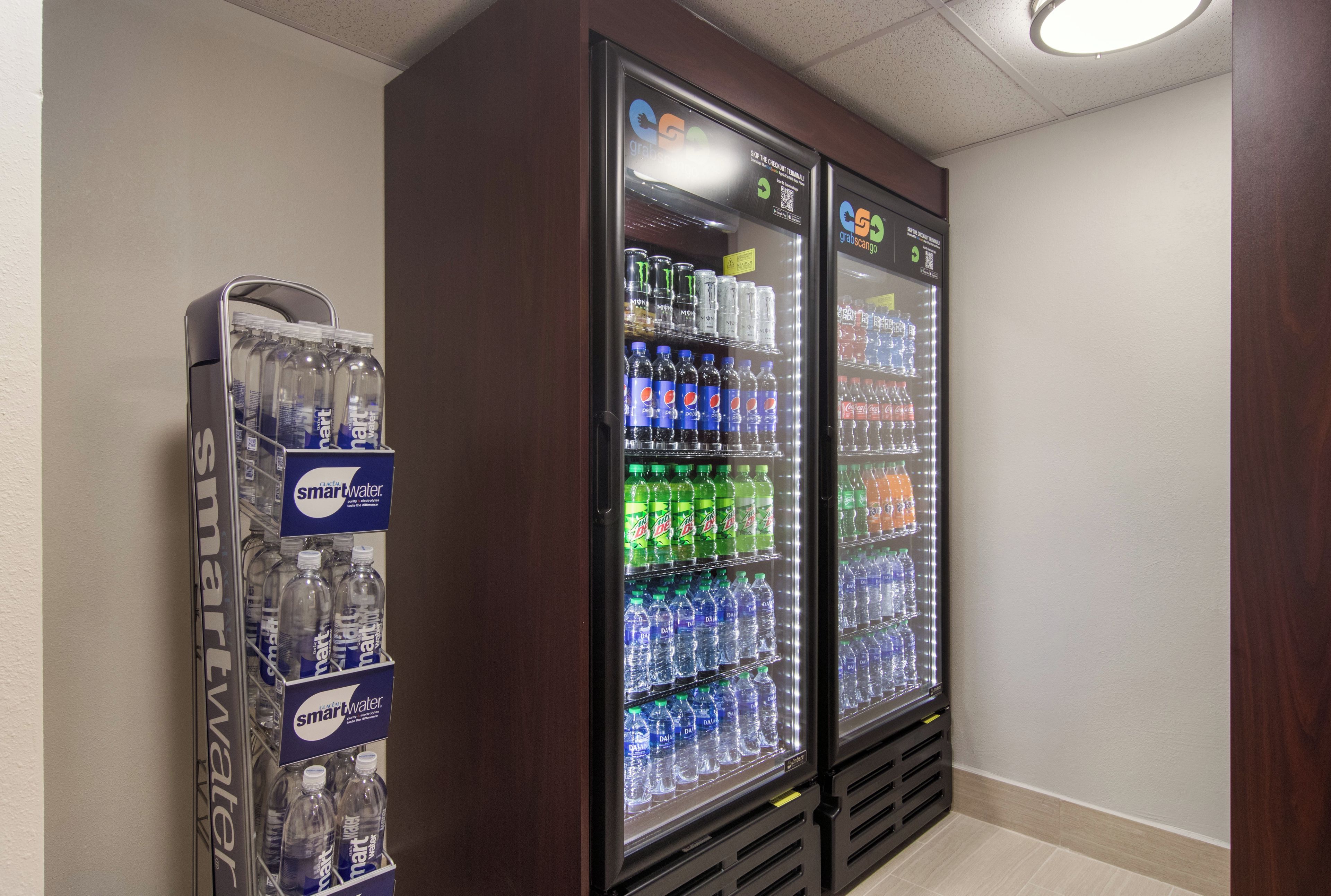 Un distributeur automatique proposant une variété de bouteilles d’eau et de boissons gazeuses.