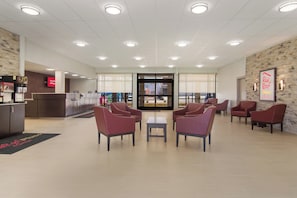 A hotel lobby with seating, a reception desk, and a view through a glass door. - Red Roof Inn PLUS+ & Suites Erie (Erie)