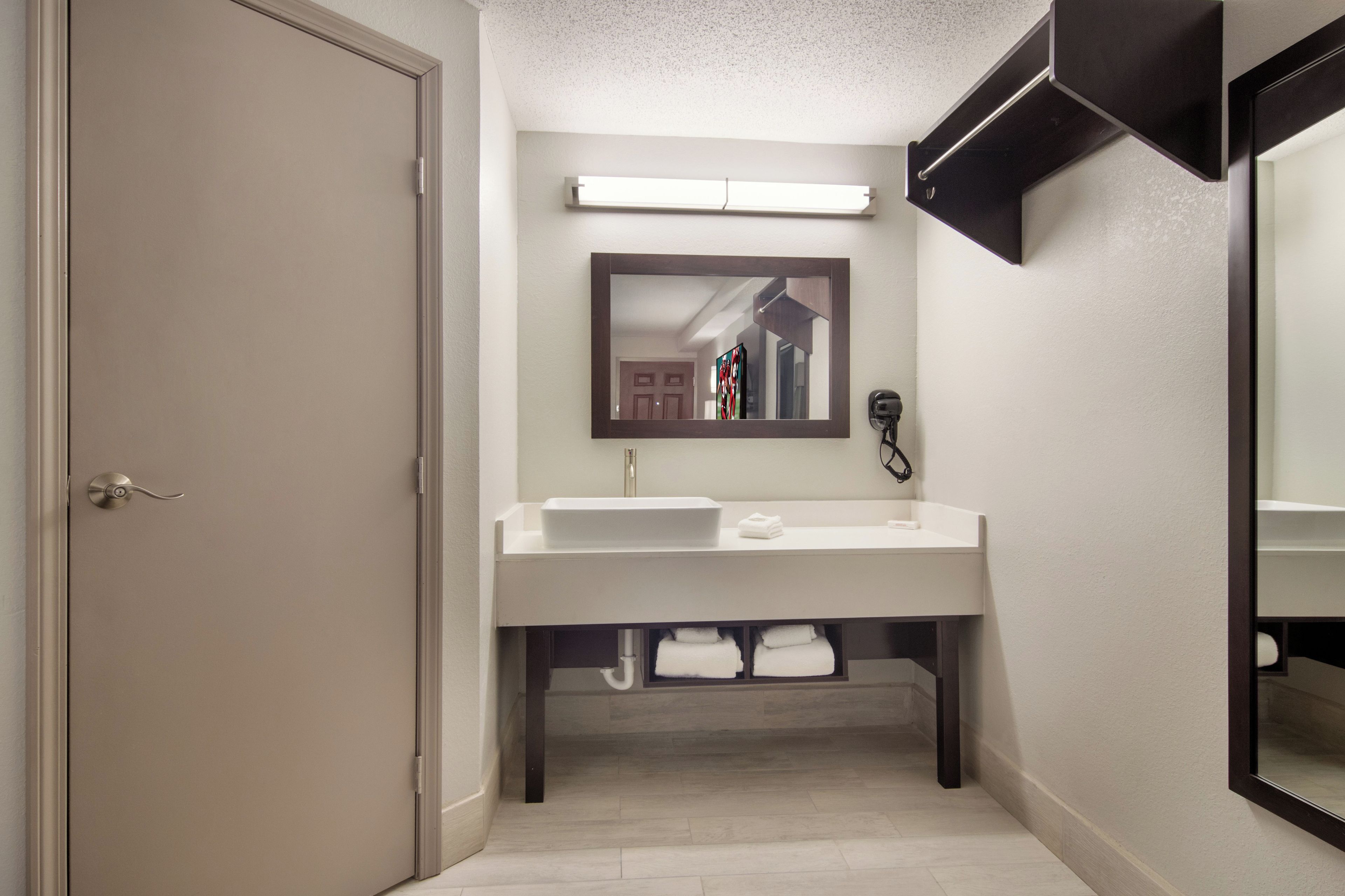 A bathroom with a double sink, a mirror, a towel rack, and a telephone.