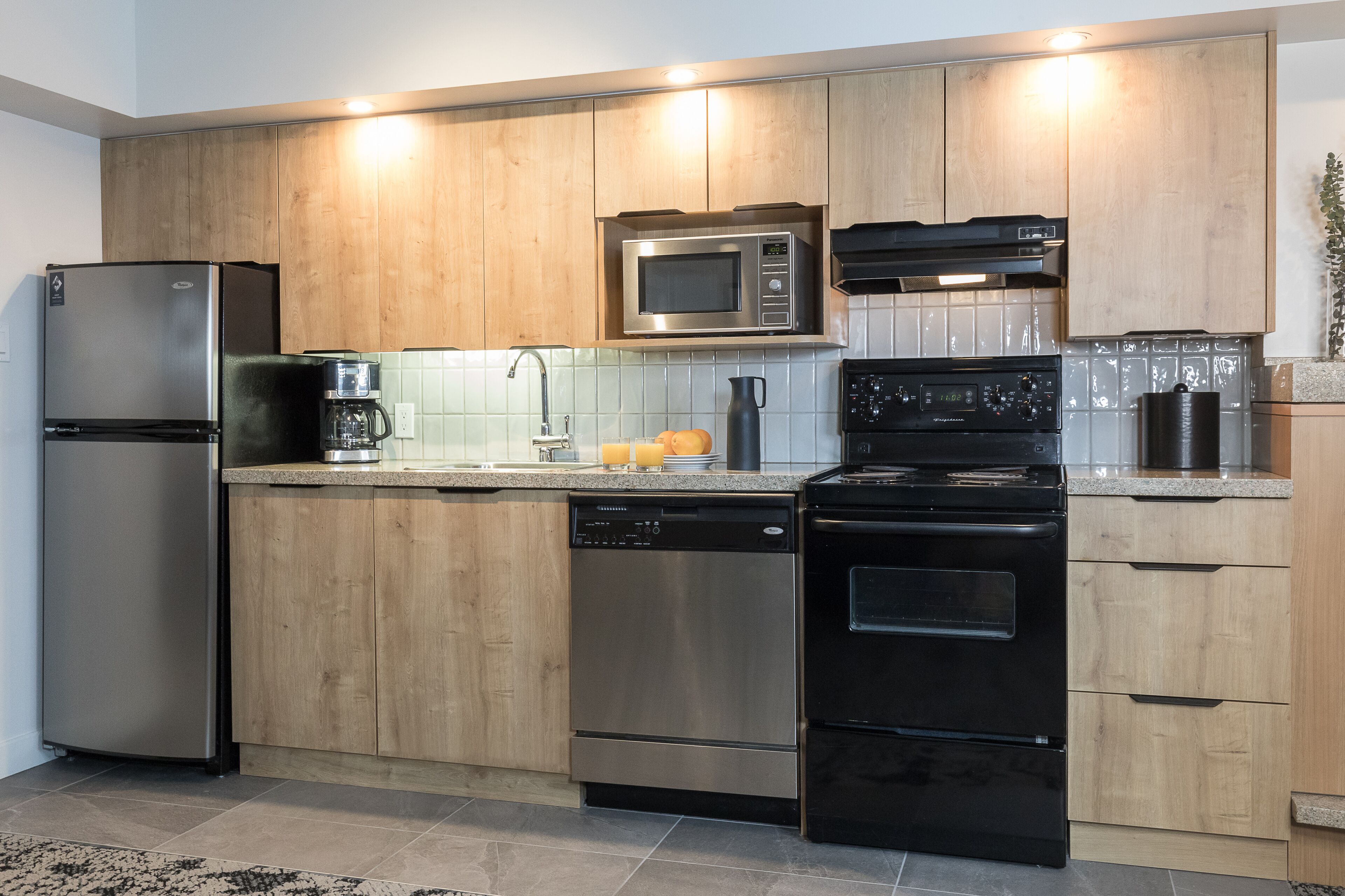 Una cocina moderna con electrodomésticos de acero inoxidable, armarios de madera y salpicadero de azulejos.