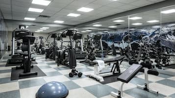 A gym with various exercise equipment, a mirrored wall, and a checkered floor.