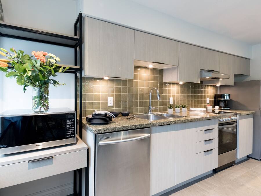 A modern kitchen with stainless steel appliances, a granite countertop, and light wood cabinetry.