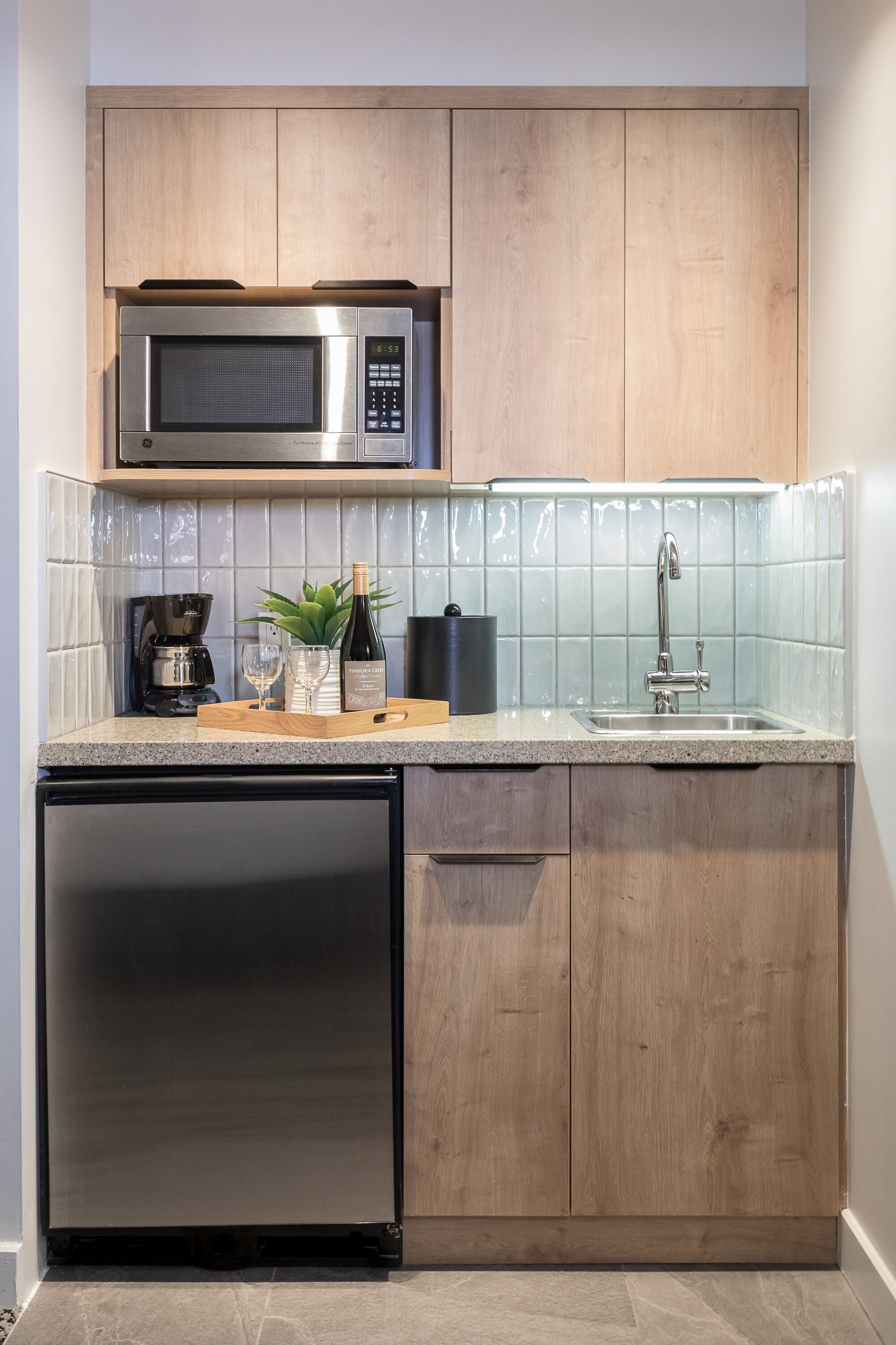 Una cocina compacta con microondas integrado, un lavabo y lavavajillas.