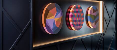 Pared con tres piezas de arte geométrico iluminadas.