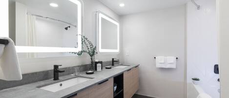 A modern bathroom with two sinks, a large mirror, and a shower area.