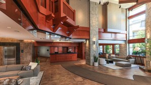 A spacious lobby with a modern design, featuring a large reception desk, comfortable seating areas, and a prominent staircase.
