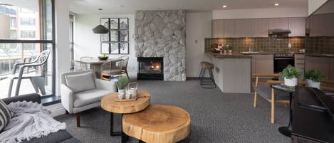 Uma sala de estar moderna com lareira, área de jantar e cozinha com parede de pedra decorativa.