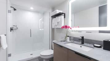 A modern bathroom with a glass-enclosed shower, a toilet, a sink with a mirror, and a vanity with cabinets.