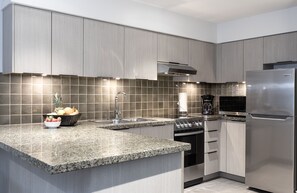 A modern kitchen with granite countertops, stainless steel appliances, and a tiled backsplash.